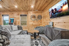 A cozy living room with a sofa, a coffee table, and a television mounted on the wall. - The Brookshire! Premium View | Hot Tub | Top 10% (Sevierville)