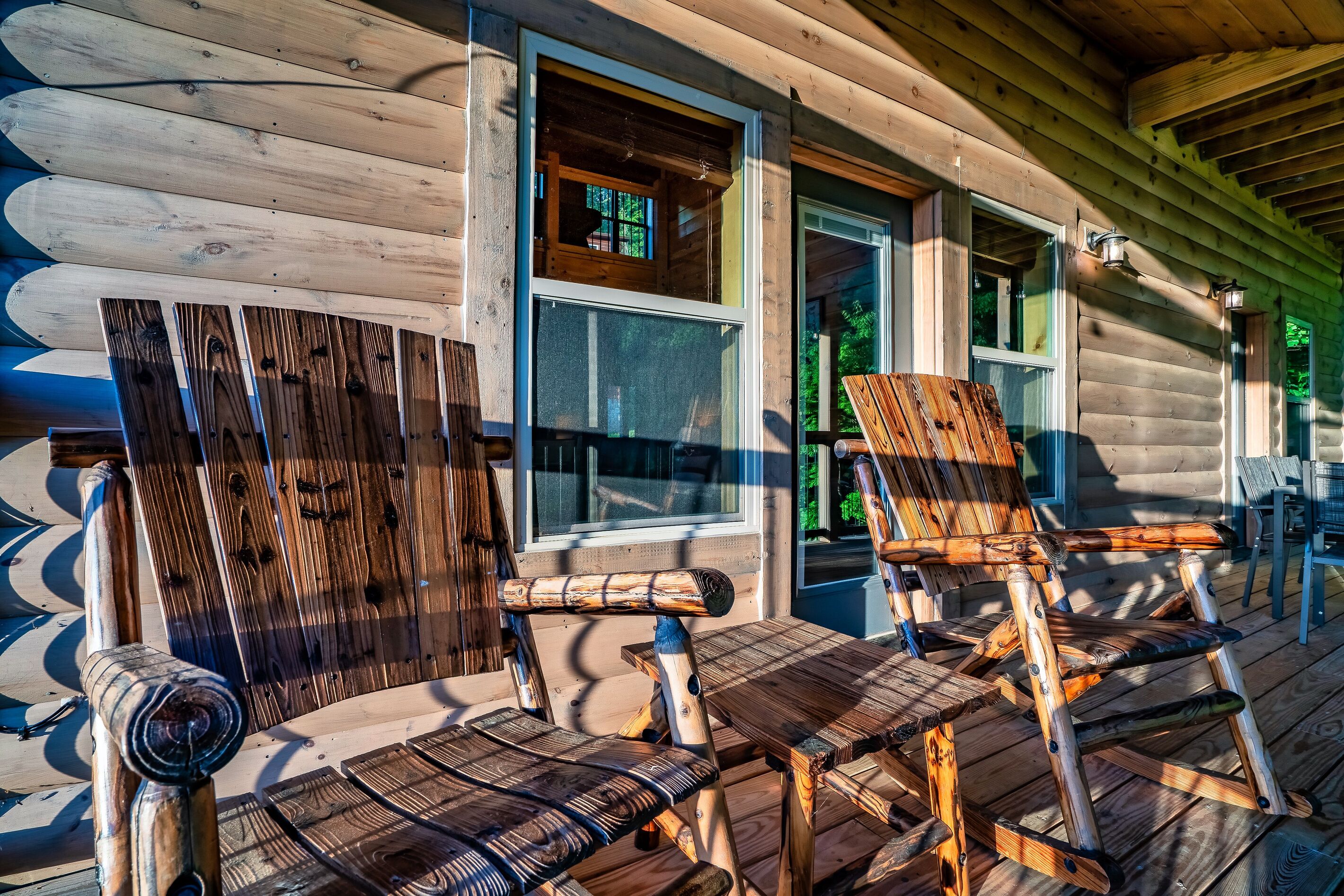 Eine Holzhütte mit Veranda, ausgestattet mit zwei hölzernen Schaukelstühlen und einem Tisch.