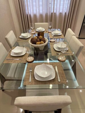 A dining table set for six with a central bowl of cookies, surrounded by plates, glasses, and cutlery.
