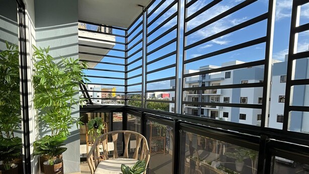 A balcony with wicker furniture, potted plants, and a hanging light fixture.
