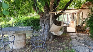 A rustic outdoor seating area with a stone table, metal chairs, and a hammock. - Provencal house with private pool (MONS)