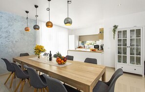 A modern dining area with a wooden table, grey upholstered chairs, and pendant lighting. - Beautiful home in Vodnjan (Vodnjan)