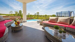 Un espace extérieur aménagé avec des meubles en osier, une piscine et une vue sur un paysage verdoyant.