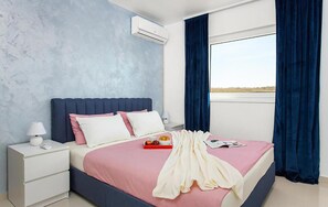 A bedroom with a bed, nightstand, lamp, air conditioning unit, and a window with curtains. - Beautiful home in Vodnjan (Vodnjan)