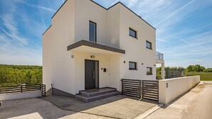 Un bâtiment moderne à deux étages, doté d’un toit plat, d’un balcon à l’étage supérieur et d’une entrée principale avec des marches.