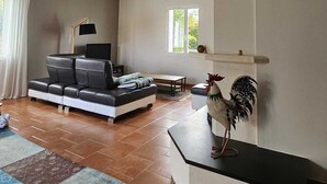 A spacious living room with a sofa, a coffee table, a lamp, and a rooster decoration. - Villa with pool in Toulouse - 5 bedrooms, garden, 10 travellers (Cugnaux)