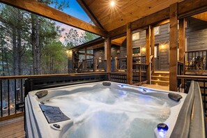 Un jacuzzi en una terraza de madera con vistas a árboles.