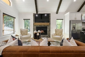 A living room with a fireplace, two armchairs, a sofa, and a television. - NEW! Updated Secluded Cabin w/ Hot Tub, Fire Pit, Outdoor Lounge & Forest Views (Broken Bow)