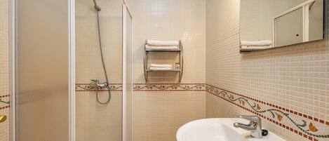 Une salle de bain avec une douche, un lavabo et un porte-serviettes.