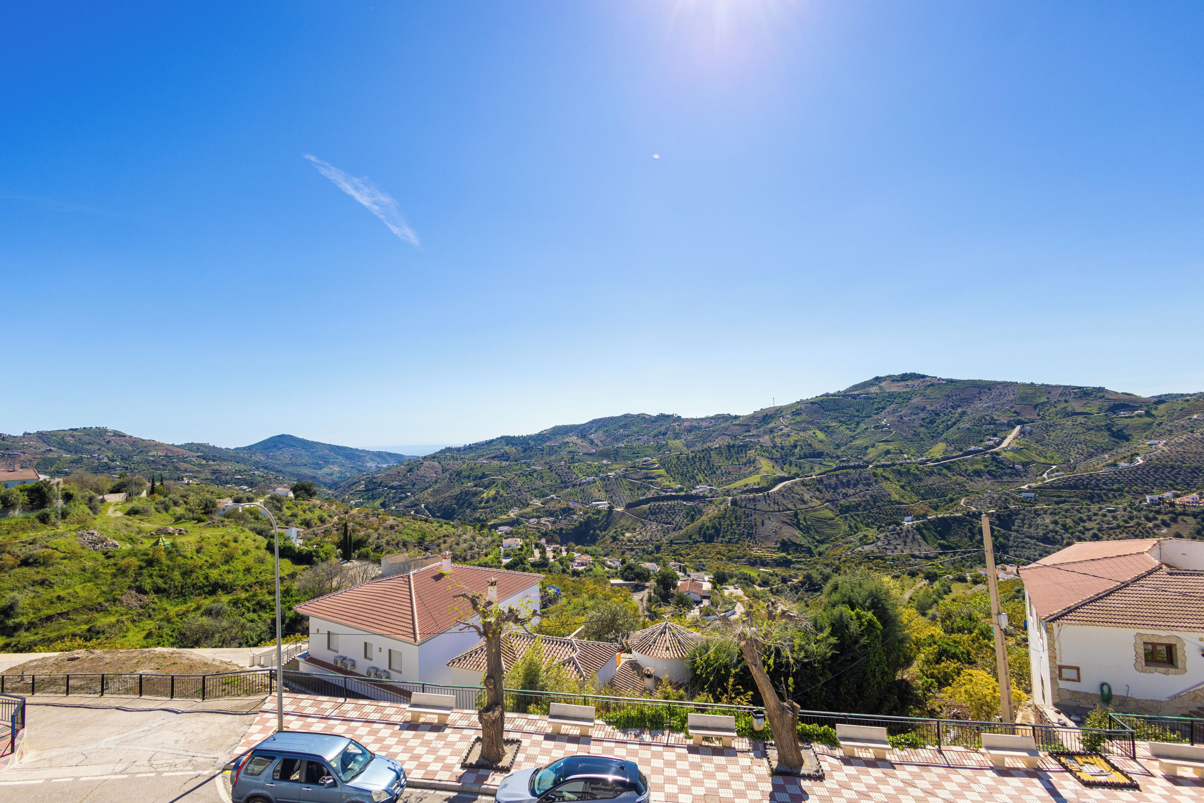 Una zona residencial con casas, un estacionamiento pavimentado y un paisaje montañoso al fondo.