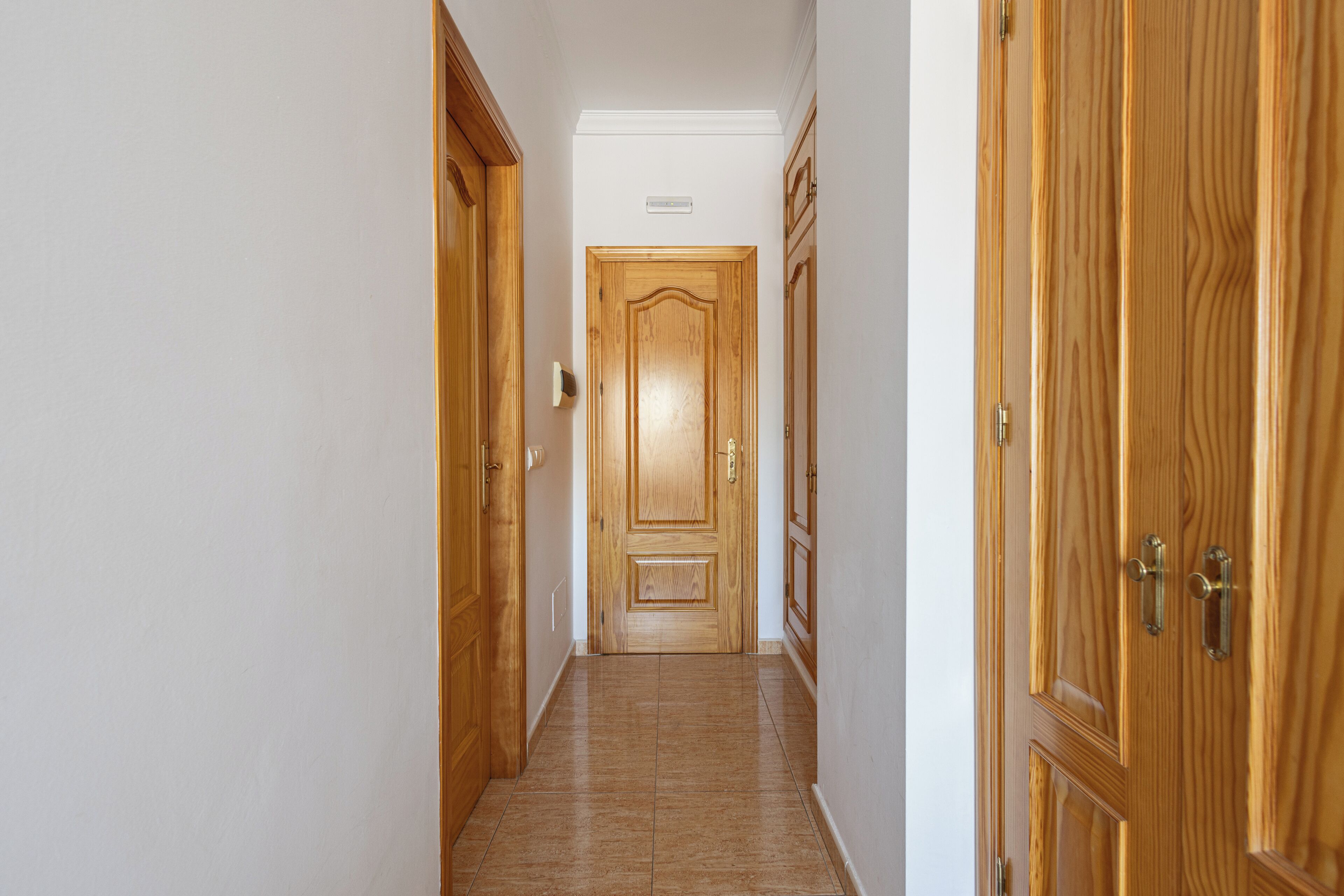A hallway with wooden doors and a tiled floor.