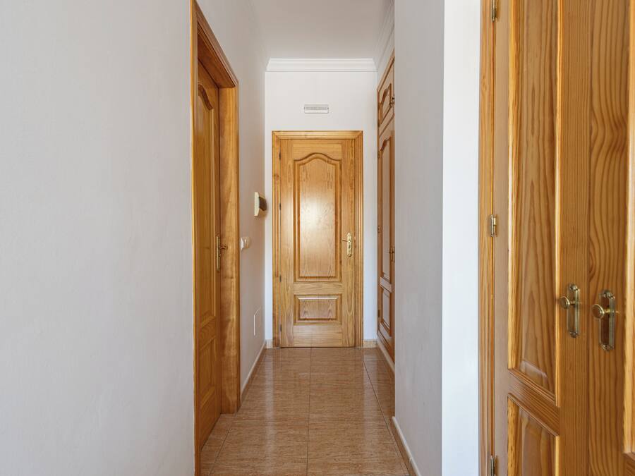 Un pasillo con puertas de madera y suelo de baldosas.