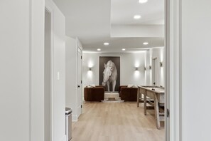 A hallway with a modern design, featuring a central staircase, two seating areas, and a large wall-mounted artwork. - Luxury Country Retreat | Sleeps 15 | Bourbon Trail (Simpsonville)