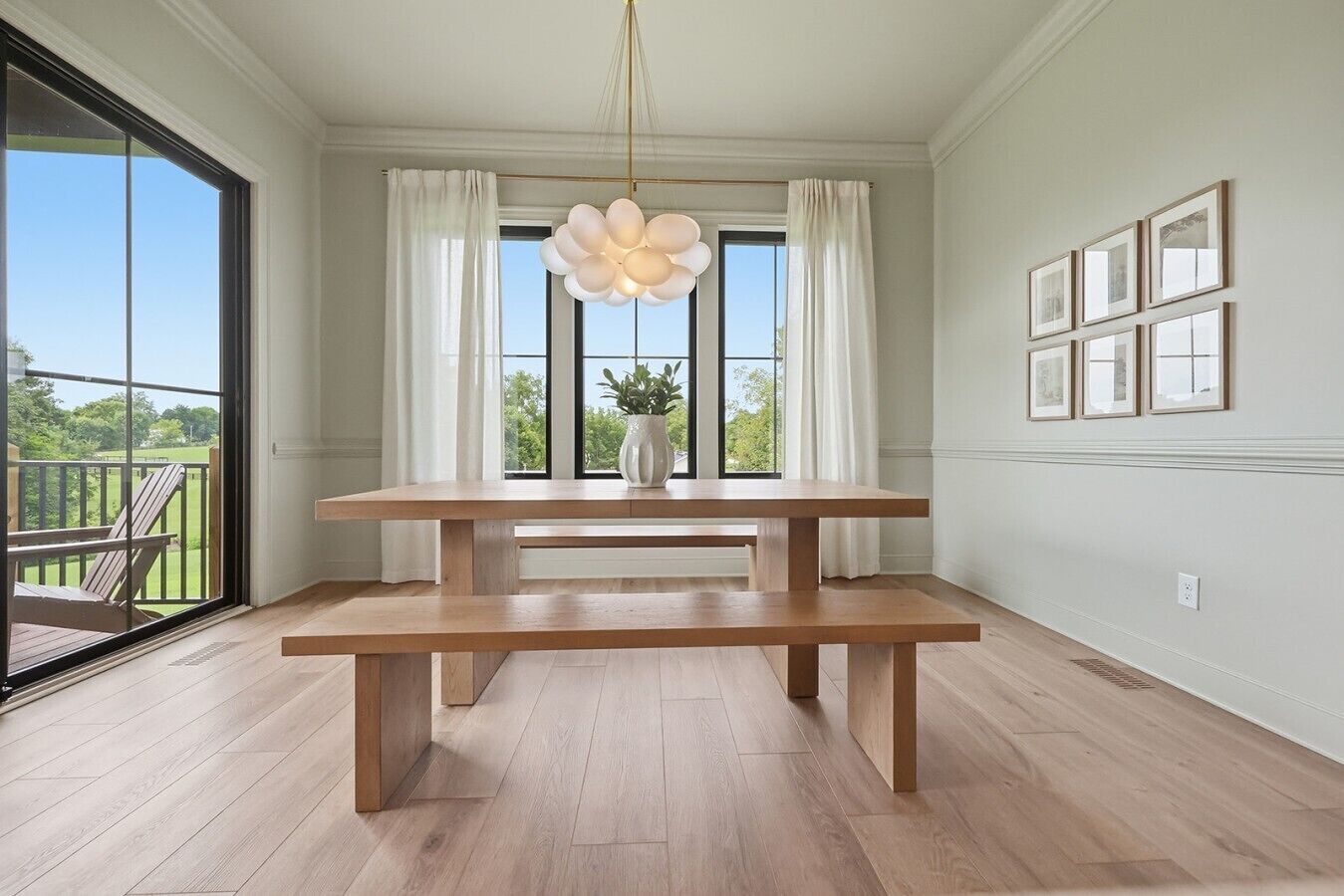 En matplats med ett träbord och bänkar, stora fönster med gardiner och utsikt över omgivningen.
