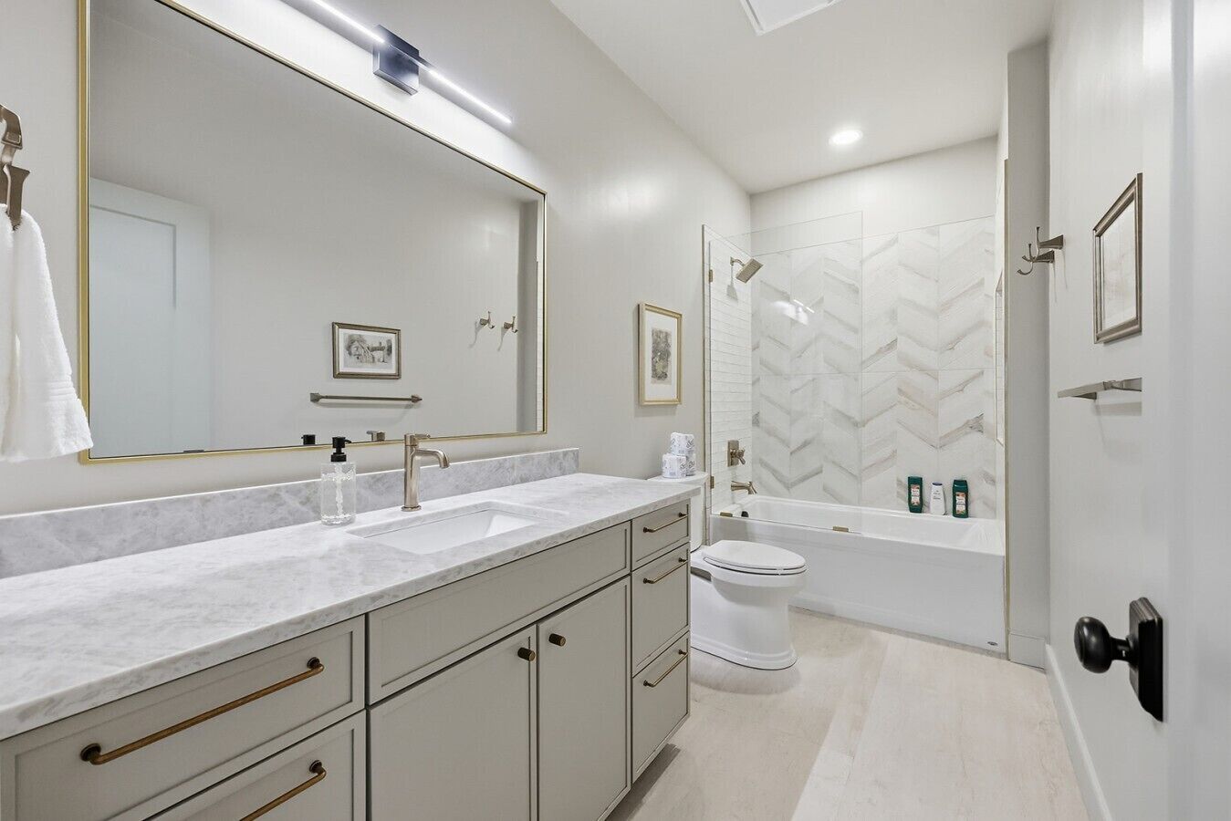 Un baño moderno con un espejo grande, un lavabo, un inodoro y una zona de ducha.