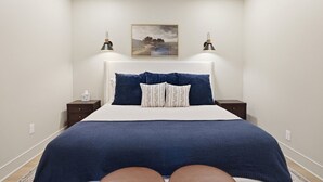 Ein Schlafzimmer mit einem Bett, zwei Nachttischen, einer Wandlampe und einem gerahmten Bild an der Wand.
