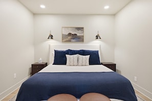 Ein Schlafzimmer mit einem Bett, zwei Nachttischen, einer Wandlampe und einem gerahmten Bild an der Wand.