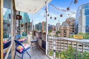 A balcony with chairs and a table, overlooking a cityscape with buildings and greenery. - Dúplex Skyline apartment 2D Wifi Near Costanera Center (Providencia)