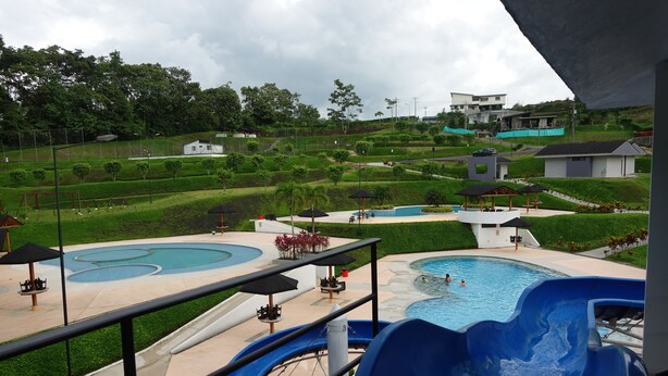 A pool area with a water slide, lounge chairs, and a view of the surrounding landscape.