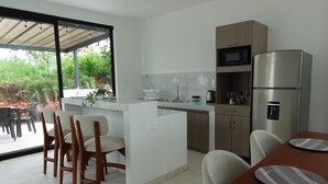 A modern kitchen with a built-in island, stainless steel appliances, and a dining area with chairs and a table.