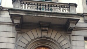 A double wooden door with a decorative arch above it, set in a building with stone walls and a small balcony. - A Modino Florence Centre Suites (Florence)