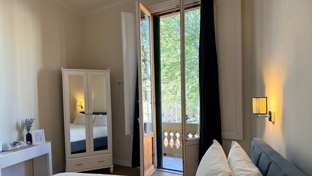 A hotel room with a bed, a wardrobe, a bedside table with a lamp, and a window with a view of the outside. - A Modino Florence Centre Suites (Florence)