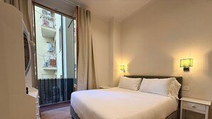 A hotel room with a bed, bedside tables, a balcony with curtains, and a view of a building with balconies. - A Modino Florence Centre Suites (Florence)