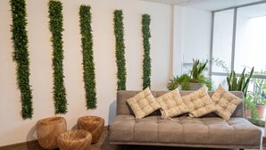 A modern living room with a sofa, decorative pillows, and vertical green plant arrangements on the wall. - Historic Center Quito by Otium (Quito)