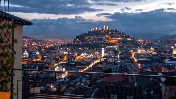 A cityscape with a prominent hilltop structure, a bench, and a railing. - Historic Center Quito by Otium (Quito)