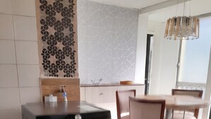 A modern kitchen with a built-in washer, a dining area with wooden chairs, and a decorative backsplash. - Historic Center Quito by Otium (Quito)