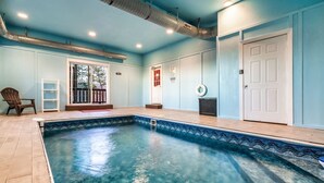 En swimmingpool med en kakelbeklädd poolkant, en dörr och en stol.