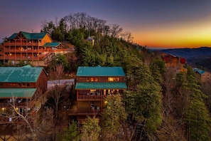Eine mehrstöckige Lodge mit Gründach, umgeben von dichtem Wald, mit mehreren Balkonen.