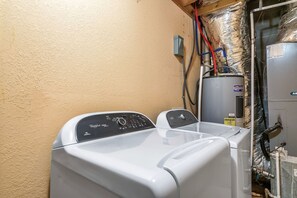 A laundry room with two front-loading washing machines, a water heater, and visible plumbing. - Beaver's Mountaintop Retreat! Pool Cabin | Top 5% (Pigeon Forge)