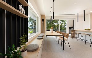A modern dining area with a long table, chairs, and a kitchen in the background. - Cozy home in Malinska with sauna (Malinska)