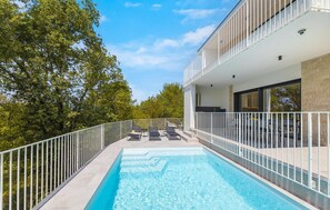 A modern outdoor swimming pool with a white railing, lounge chairs, and a balcony with a glass railing. - Cozy home in Malinska with sauna (Malinska)
