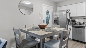 Une cuisine moderne dotée d’appareils électroménagers en acier inoxydable, une table à manger avec des sets de table et un miroir décoratif.