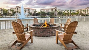 A fire pit with four Adirondack chairs, a sandy beach, and a water fountain in the background. - Marriott Grande Vista  Resort 2 bed/2 Bath w Kitchen in Orlando near Theme Parks (Orlando)