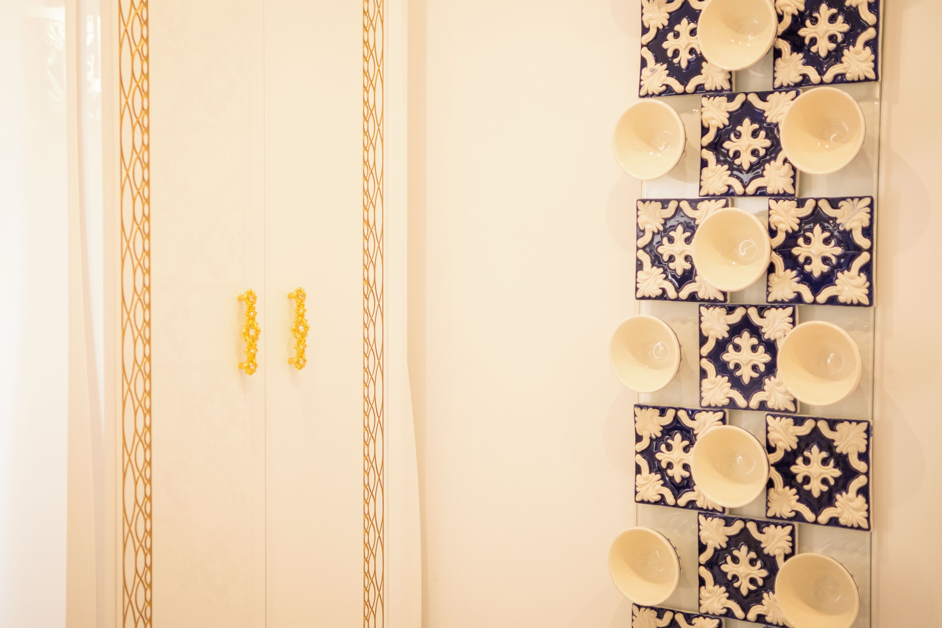 Casa de banho com porta branca, suporte de toalhas e lavatório fixado na parede com painel de azulejos decorativos.