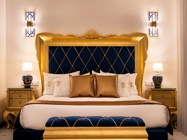 A luxurious bed with a gold headboard, white and brown pillows, and matching nightstands with lamps. - Solar Antigo Luxury Porto Aeroporto (Maia)