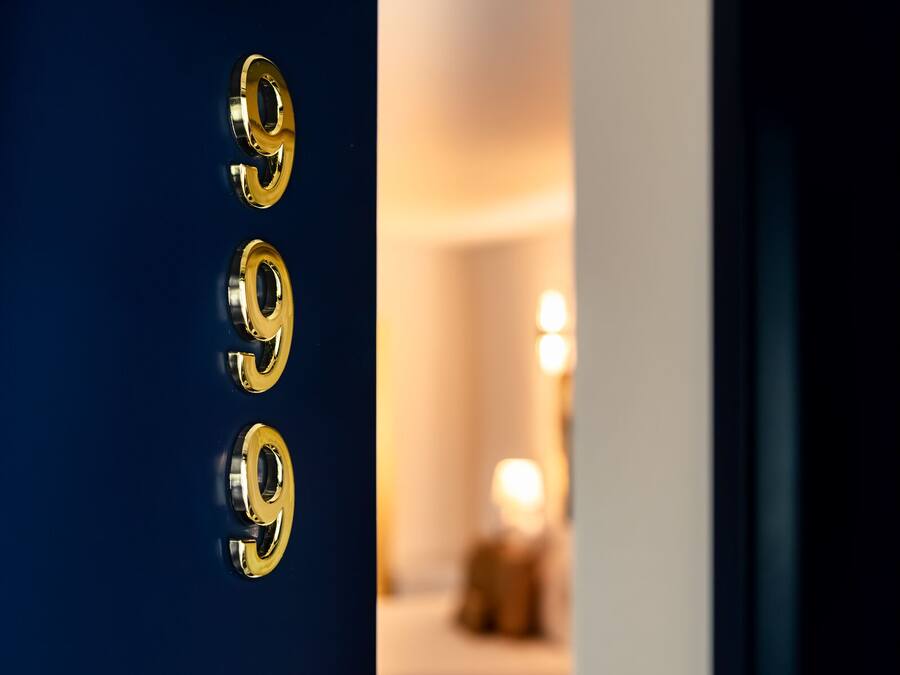 Uma porta com três números dourados '9', indicando o número de um quarto de hotel.