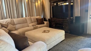 Un saló amb un sofà modular, un televisor de pantalla plana i un moble de roba negra de fusta.