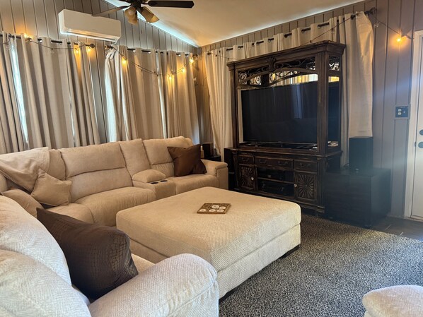 A living room with a sectional sofa, a flat-screen TV, and a dark wooden entertainment center.