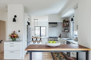 A modern kitchen with white cabinetry, a wooden dining table, and a bowl of apples. - Welcome to your North Boulder home base 4 Bedrooms, 3.5 Bathrooms. (Boulder)