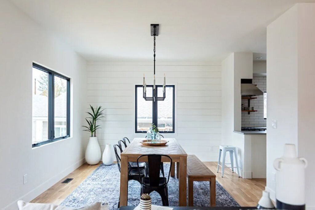Een moderne eethoek met een houten tafel, stoelen, een kroonluchter en uitzicht op de keuken.