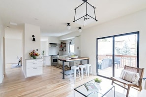A modern kitchen with a central island, white cabinetry, and a dining area with stools. - Welcome to your North Boulder home base 4 Bedrooms, 3.5 Bathrooms. (Boulder)