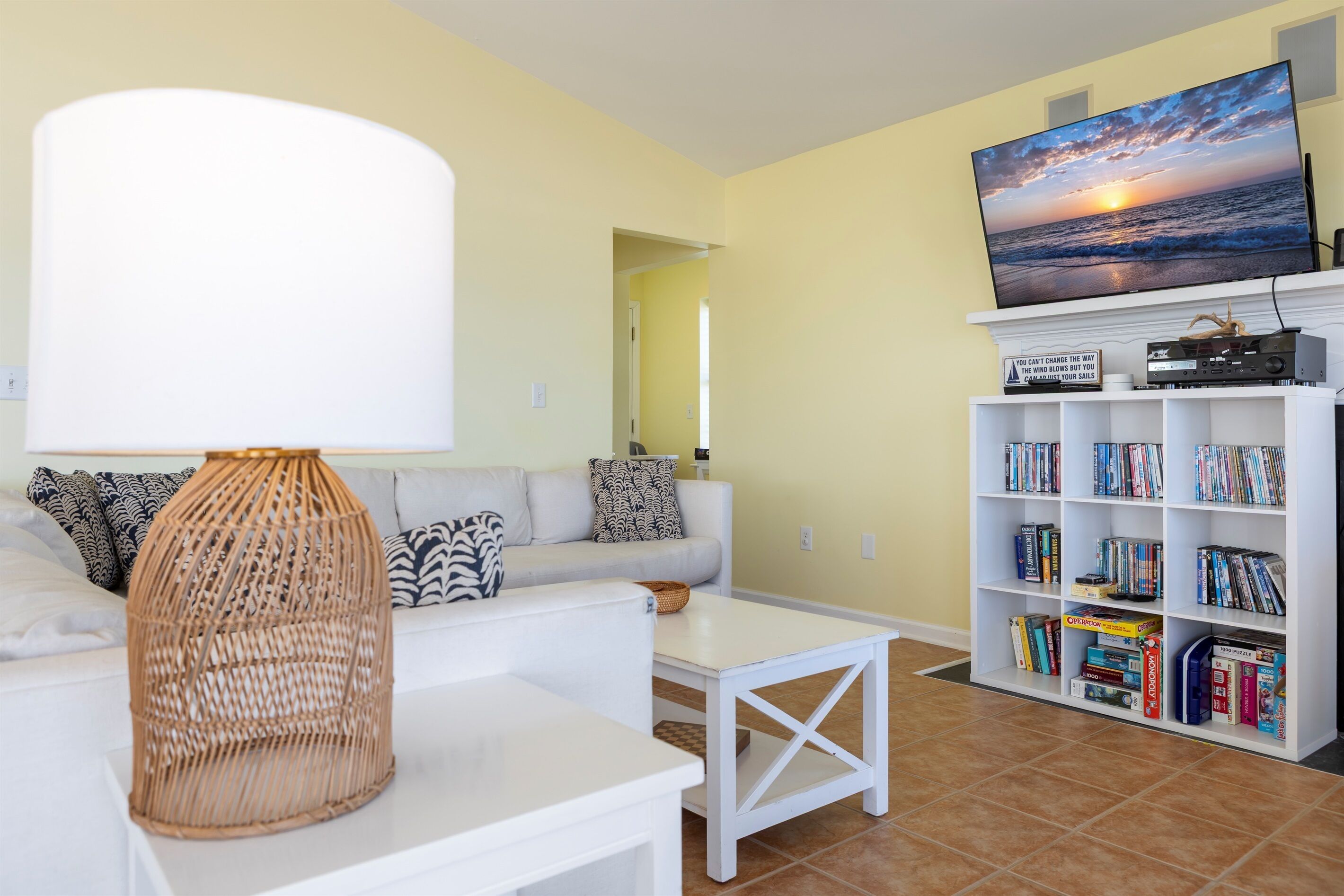 A living room with a white sofa, a coffee table, a TV on a stand, and a bookshelf with books.