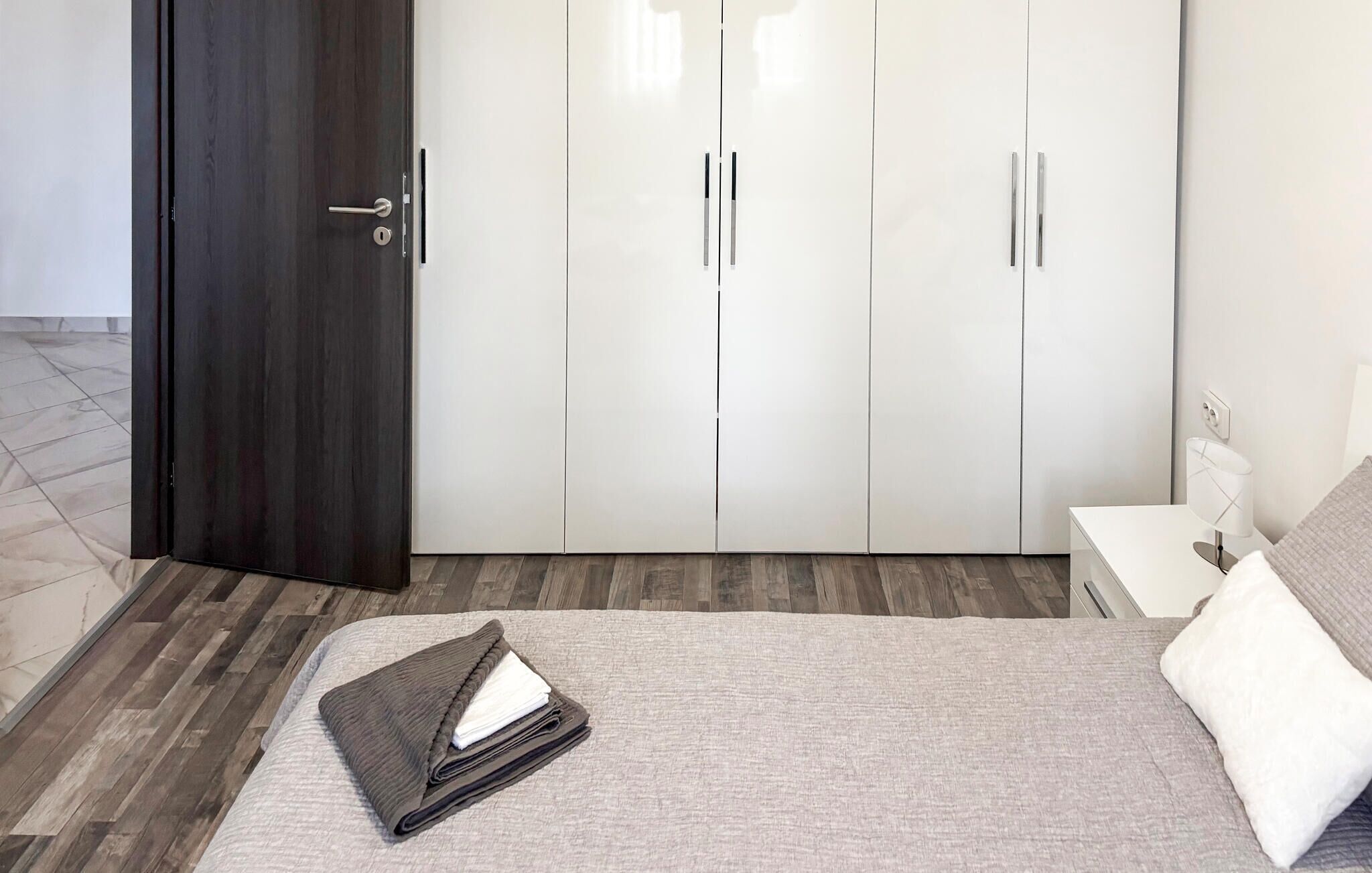 Een slaapkamer met een bed, een kast, een nachtkastje en een bijzettafeltje.