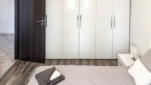 Ein Schlafzimmer mit Bett, Kleiderschrank, Nachttisch und Ablagefläche.