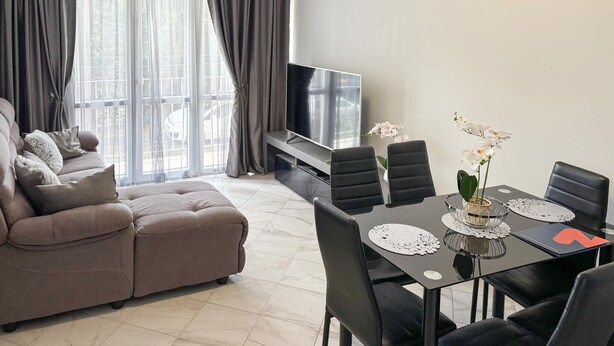 Ein modernes Wohnzimmer mit Sofa, Fernseher, Esstisch, Stühlen und Balkonblick.