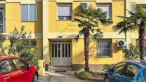 Ein gelbes Gebäude mit Tür, Fenstern und Klimaanlagen.
